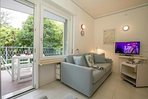 ein Wohnzimmer mit einem Sofa, einem TV und einem Balkon in der Unterkunft Riva Lago e Spiaggia Apartment 3 in Riva del Garda