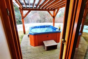 un bain à remous installé sur une terrasse avec une table dans l'établissement Forester's Hut With Whirlpool & Sauna - Happy Rentals, à Dol pri Hrastniku