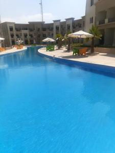 une grande piscine bleue avec des tables et des parasols dans l'établissement jenlyn chalet-families only, à Ain Sokhna