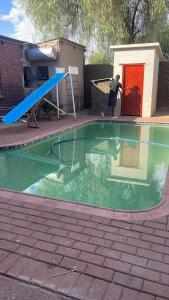 a man is playing in a swimming pool with a seesaw at Josephs Guest Home Kimberley in Kimberley