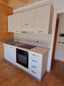 - une cuisine avec des placards blancs et une cuisinière dans l'établissement Attico in Centro: Relax&Comfort, à Baselga di Pinè