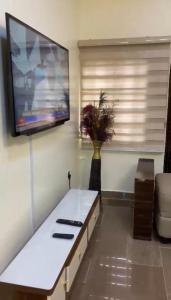 a living room with a white table and a flat screen tv at LA VIVA AIRBNB in Abuja