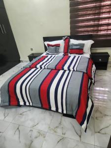 a bed with a striped comforter in a bedroom at LA VIVA AIRBNB in Abuja