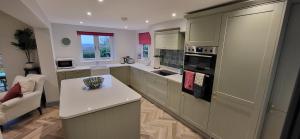 una cucina con armadi verdi e piano di lavoro bianco di Lovely 3 bed house with amazing city views & free parking a Norwich