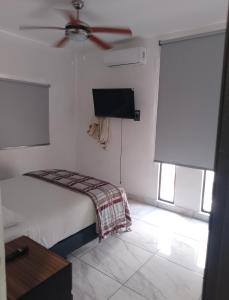 a bedroom with a bed and a ceiling fan at Hermosos Departamentos in Cozumel
