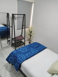 a bedroom with a bed with a blue blanket and a chair at Hermosos Departamentos in Cozumel
