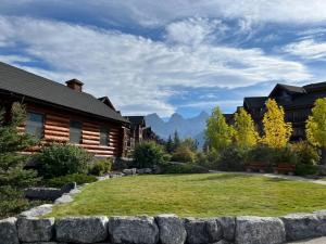 un patio con una pared de piedra en frente de una casa en L202 - A Relaxed Vacation- 2BD+2BT, Heated Pool, Hot tubs, Gym, AC, Parkade, en Canmore