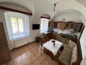a living room with a table and a kitchen at Kadovský dvůr in Sněžné