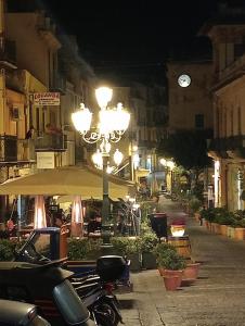 a street light with a clock in a city at night at La locanda in Cefalù