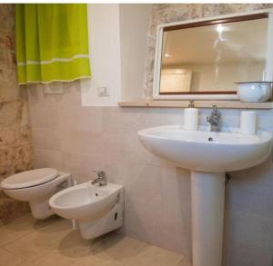 ein Badezimmer mit einem Waschbecken, einem WC und einem Spiegel in der Unterkunft Trullo Masiello in Putignano