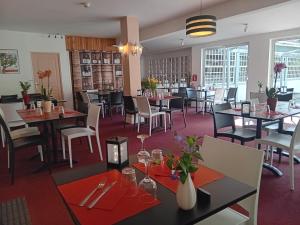 uma sala de jantar com mesas, cadeiras e janelas em Hôtel La Gravenne em Thueyts