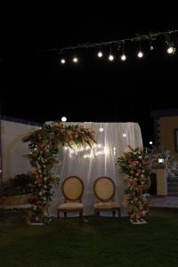 twee stoelen voor een boog met bloemen en lichten bij فيلا الواحة للحفلات والمناسبات بالعجمي/أبو يوسف in Alexandrië