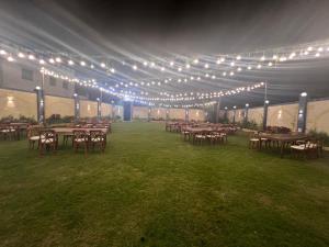 een groep tafels en stoelen onder een tent met verlichting bij فيلا الواحة للحفلات والمناسبات بالعجمي/أبو يوسف in Alexandrië