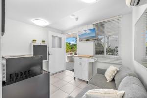 a living room with a couch and a television at Tingeera Bespoke Beachfront Apartments in Hervey Bay