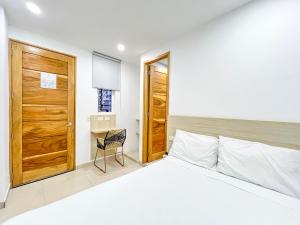 1 dormitorio con 1 cama y puerta de madera en Stanza Hotel Monteria, en Montería