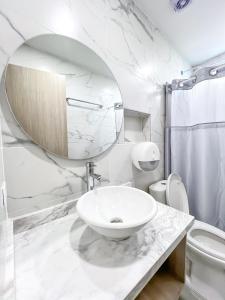 a white bathroom with a sink and a mirror at Stanza Hotel Monteria in Montería