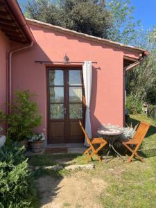 ein rosafarbenes Haus mit einem Tisch und Stühlen davor in der Unterkunft Casa Dell'Arte Botanica in Palaia