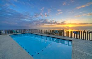 a swimming pool in front of the ocean at sunset at Laguna Village Escape 2 Home Buyout Waterfront in Padre Island