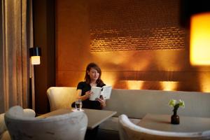 a woman sitting at a table in front of a coffee table at Le Pavillon des Lettres - Small Luxury Hotels of the World in Paris