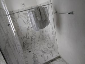 a white bathroom with a shower and a towel at Hermoso departamento in Cozumel