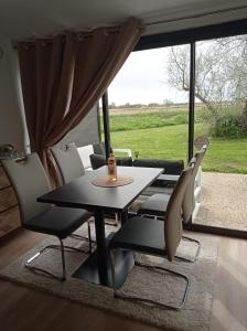 d'une salle à manger avec une table, des chaises et une fenêtre. dans l'établissement Village Camarguais Logement 4 personnes, à Arles