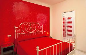 ein rotes Schlafzimmer mit einem Bett mit einer roten Wand in der Unterkunft Hotel La Maestra in Grottammare