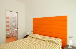 Bett mit orangefarbenem Kopfteil in einem Zimmer in der Unterkunft Hotel La Maestra in Grottammare