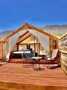a tent with two chairs and a bed on a deck at La villa Glamping in San José de Maipo