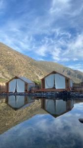 two tents sitting on top of a body of water at La villa Glamping in San José de Maipo