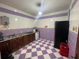 a purple and white kitchen with a black refrigerator at Belle maison au cœur de Tanger in Tangier