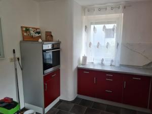 una cocina con armarios rojos y una ventana en Husic Immobilien und Handwerkerservice, en Rimbach