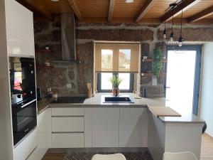 eine Küche mit weißen Schränken und einer schwarzen Arbeitsplatte in der Unterkunft Casa da Ti Mília in Trancoso