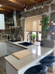eine Küche mit einer Spüle und einer Theke mit Hockern in der Unterkunft Casa da Ti Mília in Trancoso