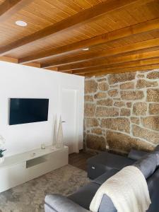 ein Wohnzimmer mit einem Sofa und einer Steinmauer in der Unterkunft Casa da Ti Mília in Trancoso