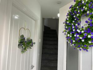a hallway with a door with a wreath of purple and white flowers at Little Welsh Hideaway - Northop - Entire 2 Bedroom House - Sleeps 3 plus Single sofa bed - Couples Retreat - Corporate - Weddings - Golf - Quiet Location - Free Parking - 10 miles from Chester in Connahs Quay