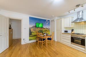 a kitchen with a table with chairs and a tv on the wall at Spectacular 3 Bed in Blackheath in London