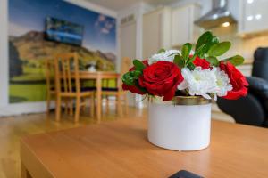 un vase blanc avec des fleurs rouges et blanches sur une table dans l'établissement Spectacular 3 Bed in Blackheath, à Londres