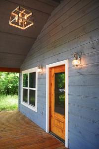 une terrasse couverte d'une maison avec une porte en bois dans l'établissement 5 STAR King Bed Lux Cabin•Netflix & Hulu 4K UHD TV, à Broken Bow