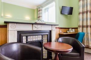 a room with a fireplace and a table and chairs at Gower Hotel in London