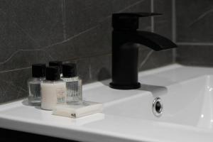 a bathroom sink with bottles of soap and a faucet at Apartment by DH ApartHotels in Peterborough