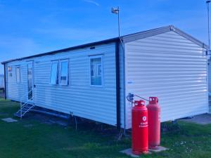 a shed with a red fire hydrant in front of it at Charming 3-Bed Caravan in Colchester Mersea island in Colchester