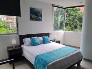 um quarto com uma cama com almofadas azuis e janelas em 404 Moderno Aparta-Suite en Versalles Tipo Loft - Cali Tower Suites & Lofts em Cali