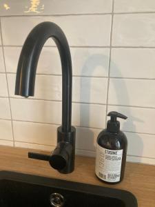 ein Waschbecken mit einem schwarzen Wasserhahn und einer Flasche Seife in der Unterkunft Zentrale Altbau-Wohnung mit Charme in Hannover