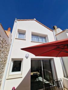 un edificio bianco con un ombrello rosso davanti di la maison de léo a Les Sables-dʼOlonne