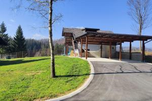 un pequeño edificio con un árbol al lado de una carretera en Počitniška hiška v gozdnem raju, en Trebče