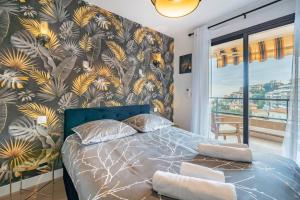 a bedroom with a blue bed with a tropical wallpaper at Monte Carlo Monaco Border, Swimming Pool, Parking, See View, Terrace in Beausoleil +37 photos