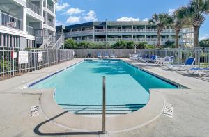 a swimming pool with chairs and a building in the background at Ocean Blvd 102 Beautiful Condo with Ocean Views in Isle of Palms