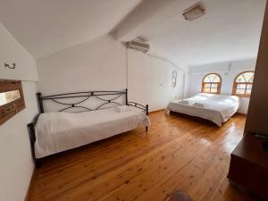 Habitación con 2 camas, suelo de madera y paredes blancas. en Casa di mare, en Loutraki