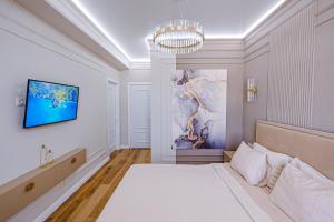 um quarto com uma cama e uma televisão na parede em New Oasis Premier-Inn flats em Chisinau