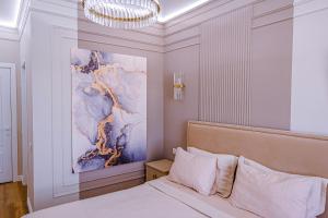 um quarto com uma cama com um quadro na parede em New Oasis Premier-Inn flats em Chisinau